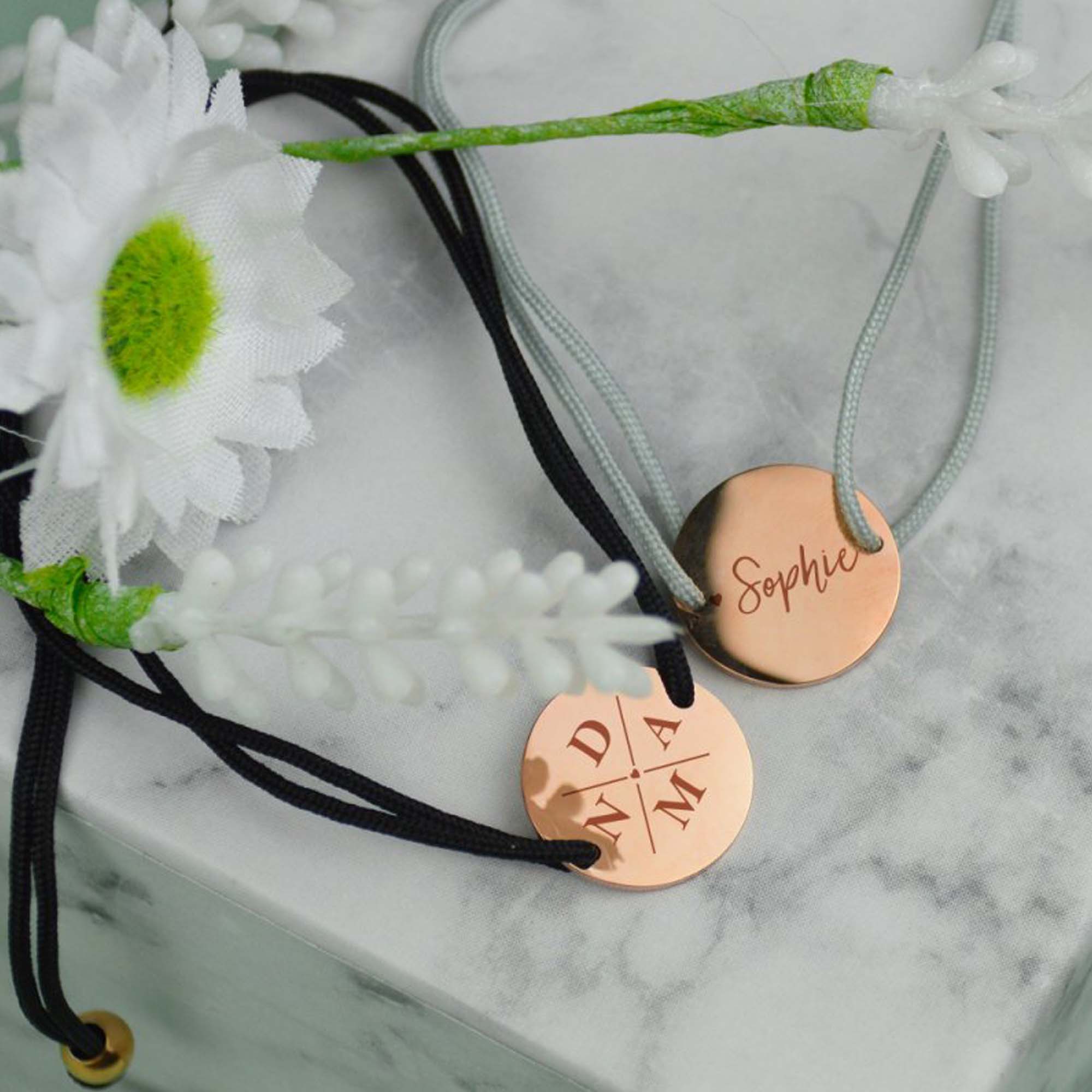 Black and grey bracelet with name in rose gold, engraved with initials and name on a marble background with flowers