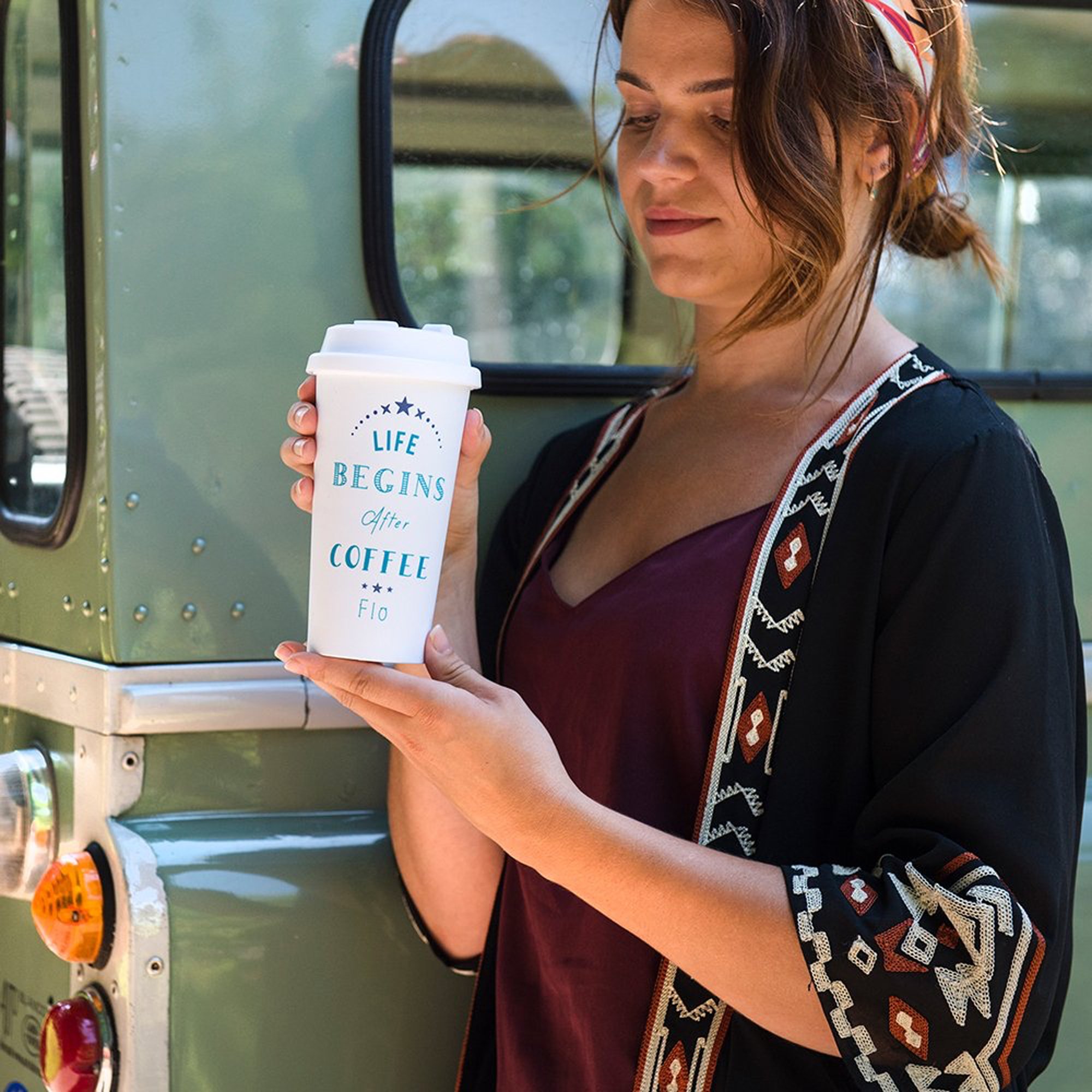 Vrouw-met-gepersonaliseerde-koffiebeker-voor-een-groene-auto
